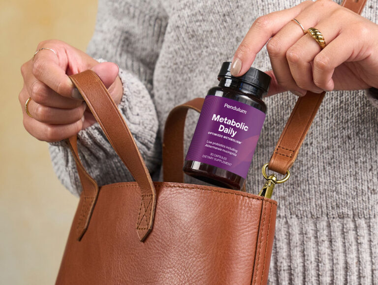 Person placing bottle of Pendulum GLP-1 daily supplement for metabolism in their bag