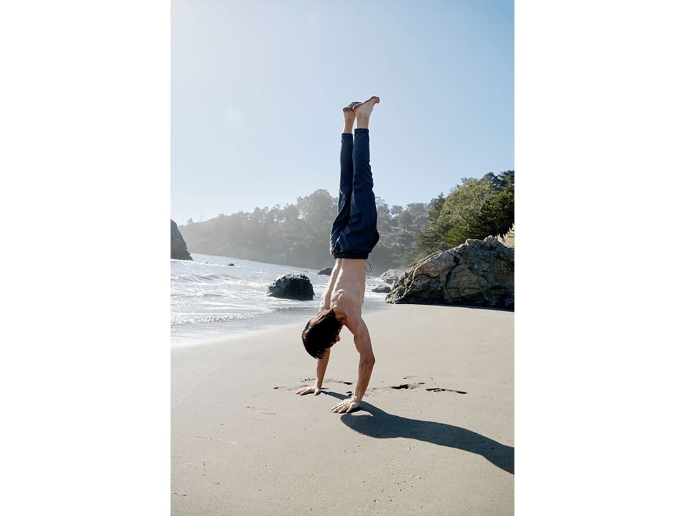 Man doing handstand on beach