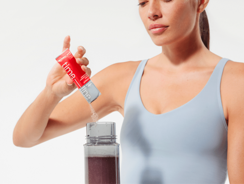 Woman adding a packet of Timeline Mitopure® to a drink